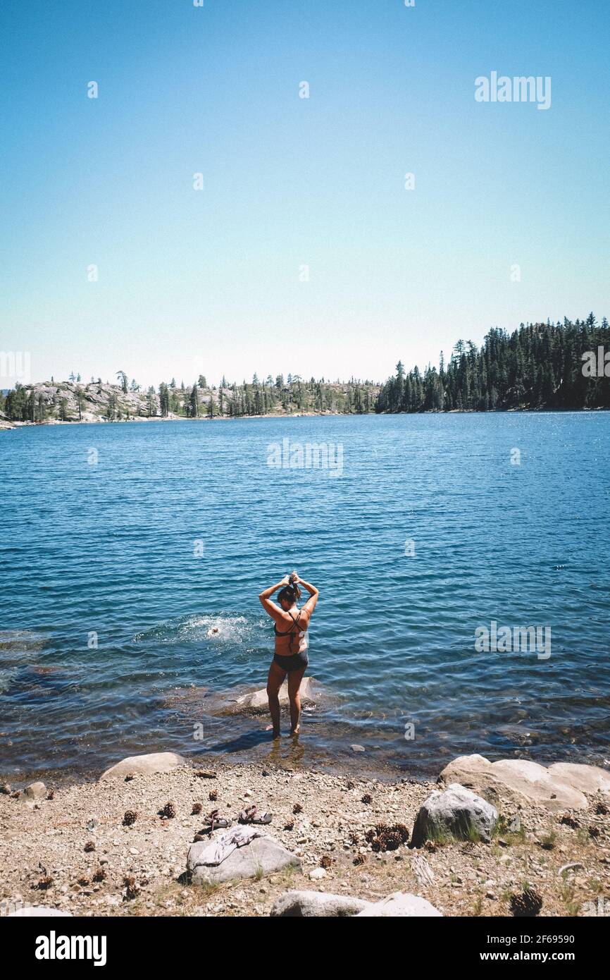 Frau im Bikini passt ihre Haare, bevor sie in Alpine springen See Stockfoto
