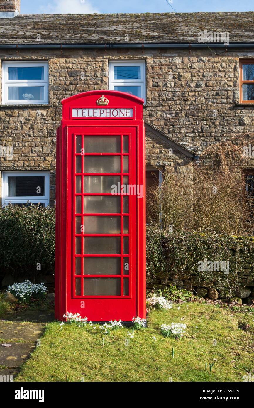 Rote Telefonbox und Schneeglöckchen in Sedbusk, Yorkshire Dales National Park Stockfoto