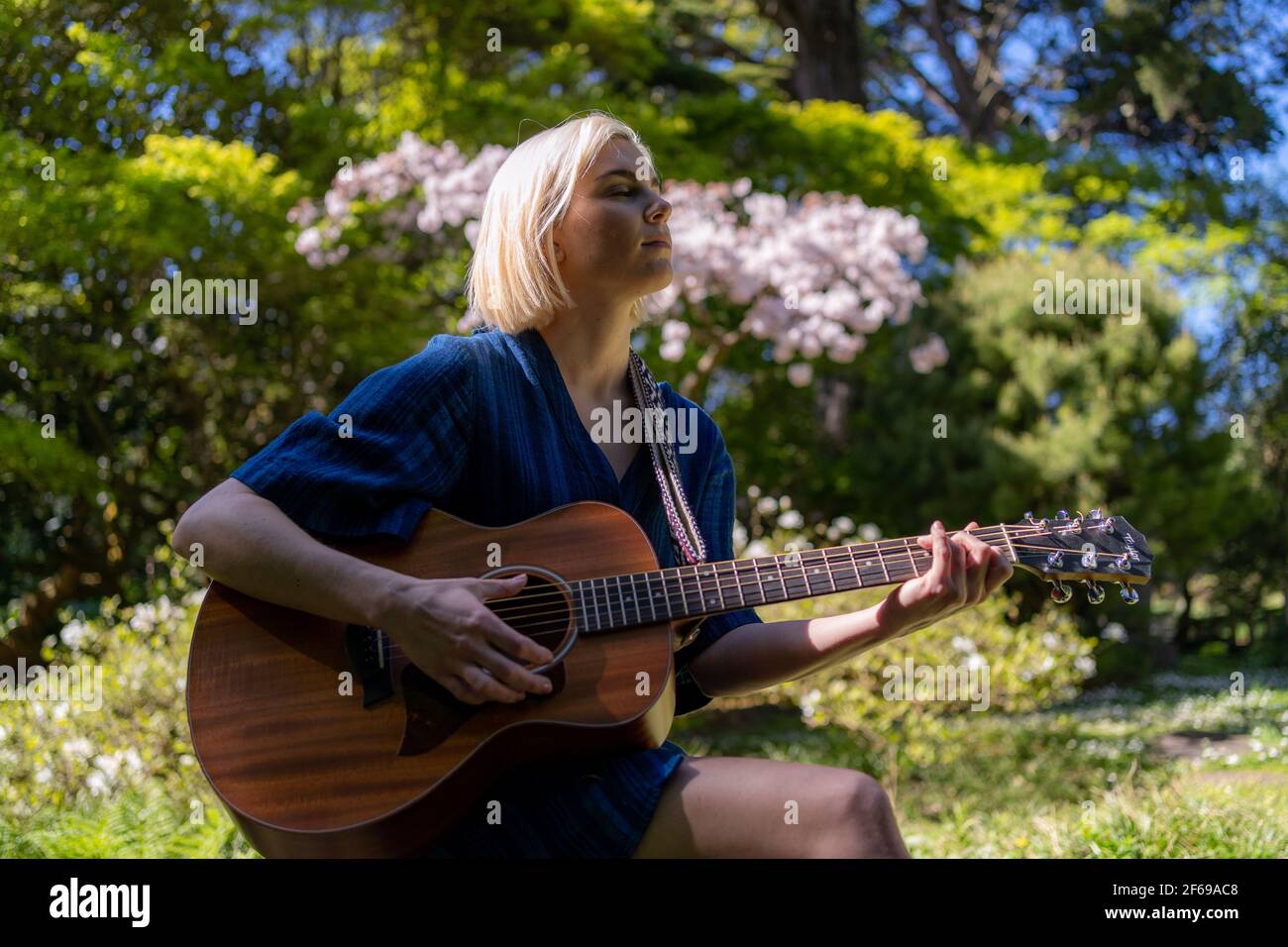 Junge Frau spielt Gitarre im japanischen Garten Stockfoto