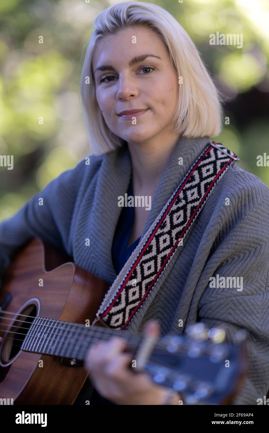 Schöne junge Frau spielt Gitarre in Redwood Hain Stockfoto