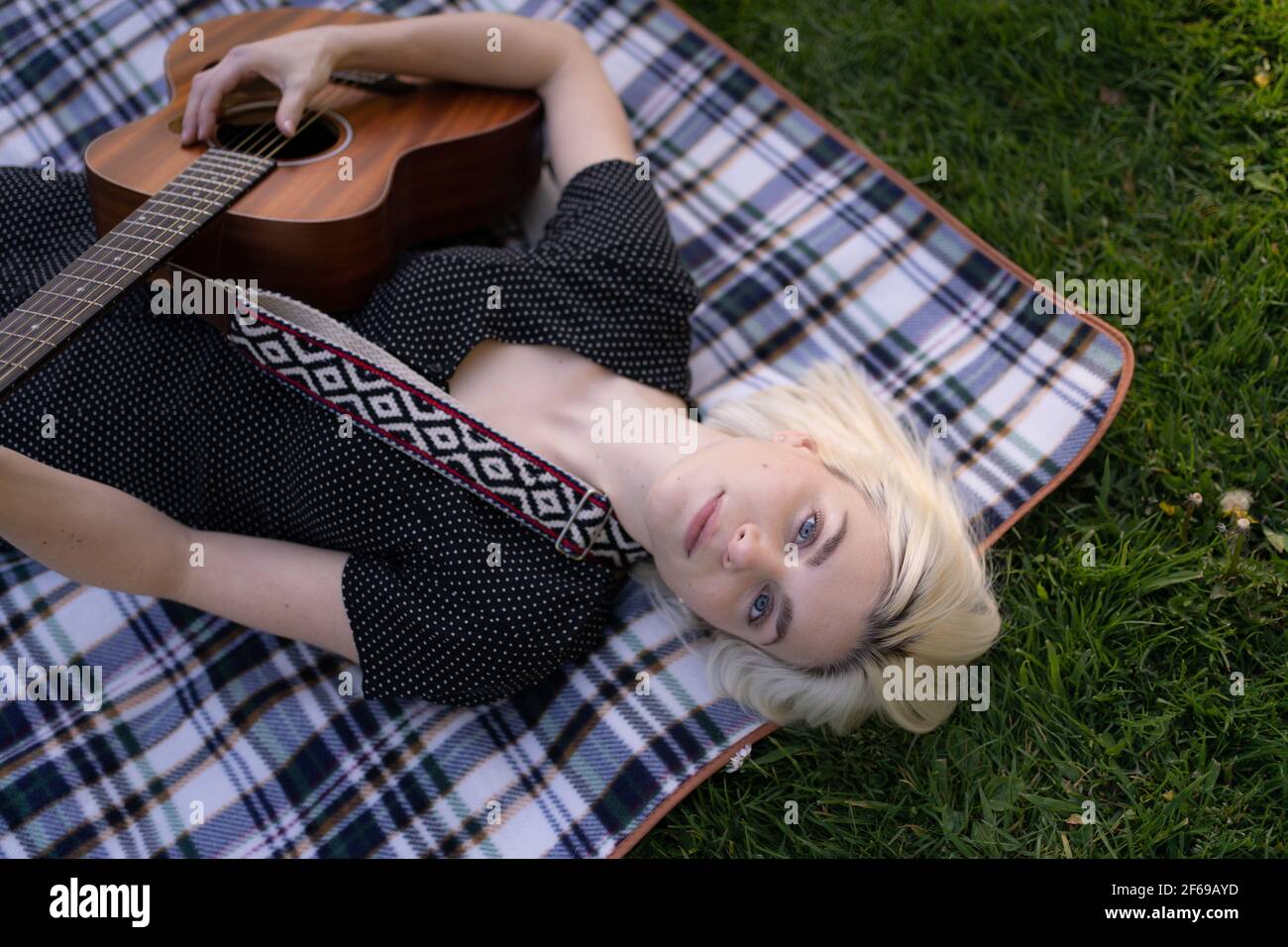 Schöne junge Frau auf Picknickdecke Gitarre spielen Stockfoto