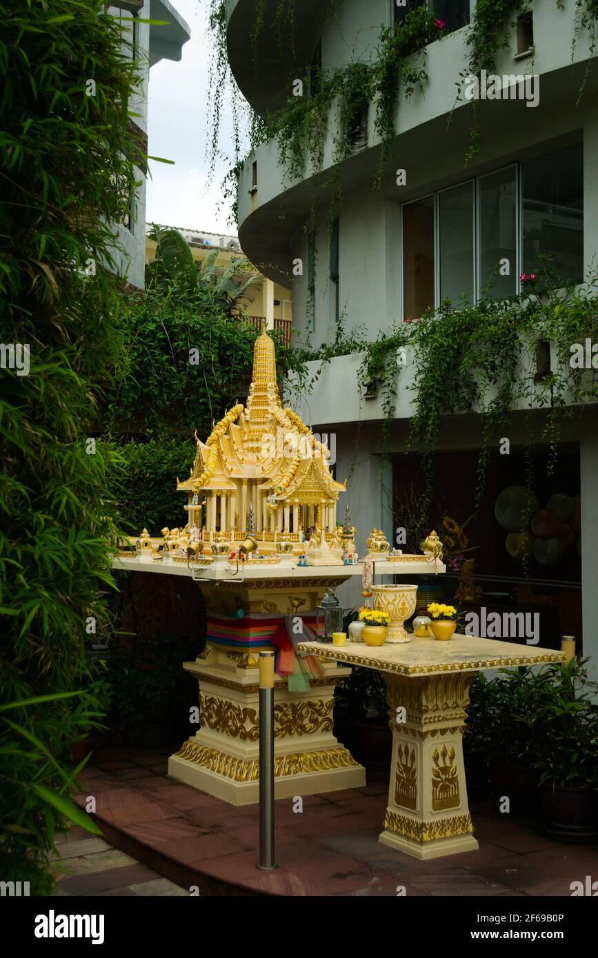 Religiöse Opfergaben in einem kleinen buddhistischen Schrein in einer Straße von Phuket, Thailand. Stockfoto