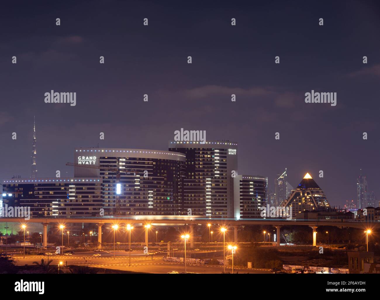 Blick auf das beleuchtete Grand Hyatt Hotel und die Wafi Mall, aufgenommen von der Gharhoud-Brücke Dubai, VAE mit Burj Khalifa und im Hintergrund in Richtung Downtowim Stockfoto