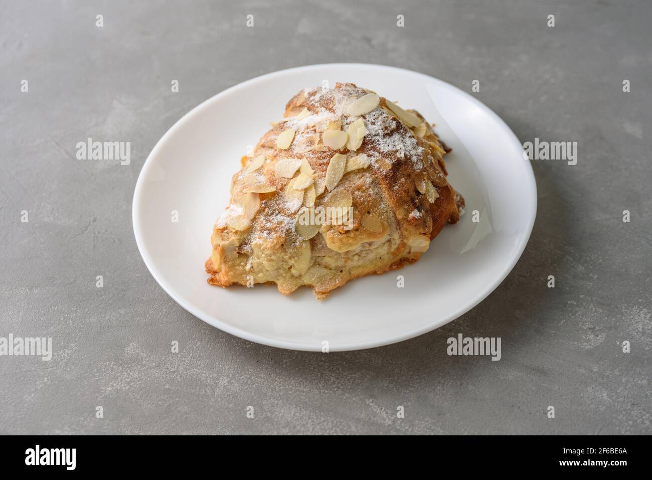Mandelcroissant auf dem Teller mit Puderzucker Stockfoto