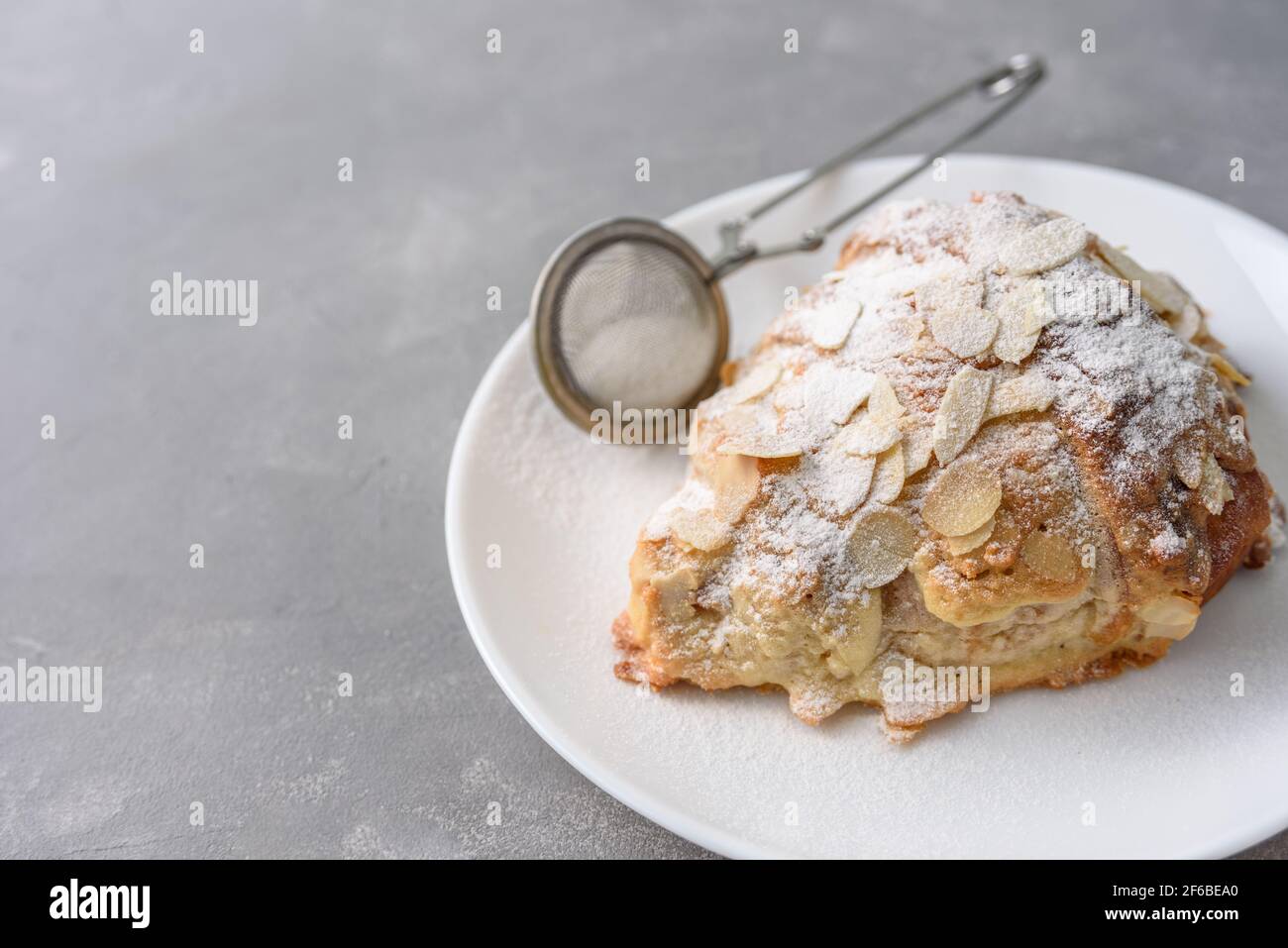 Mandelcroissant auf dem Teller mit Puderzucker Stockfoto