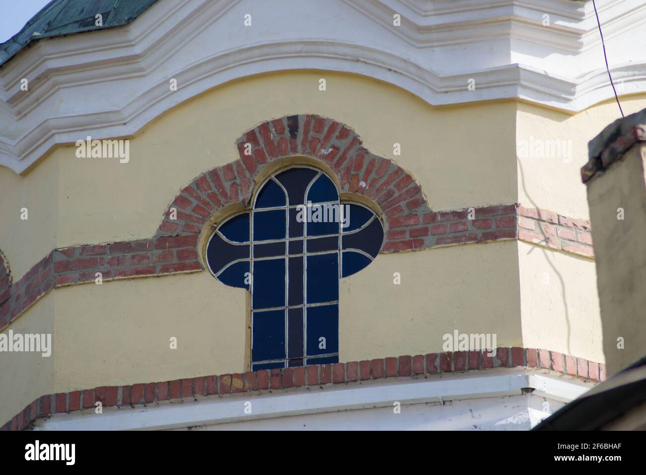 Gelbe und orange Steinmauer einer Kirche, kreuzförmige Fenster, religiöses Gebäude, architektonische Details, Nahaufnahme Stockfoto