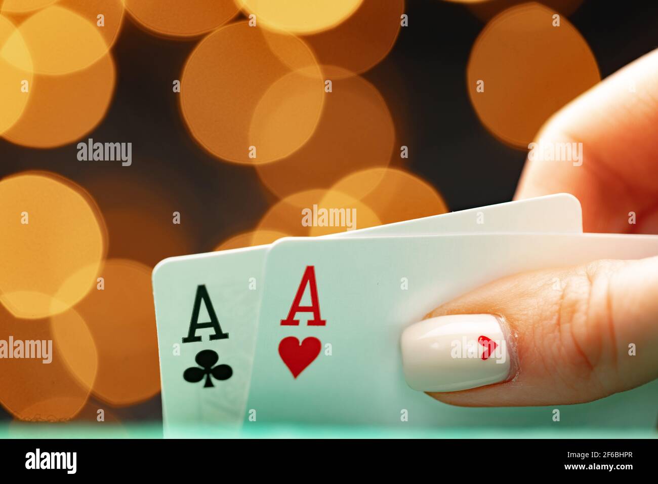 Weibliche Hand hält Spielkarten gegen Bokeh Hintergrund Stockfoto