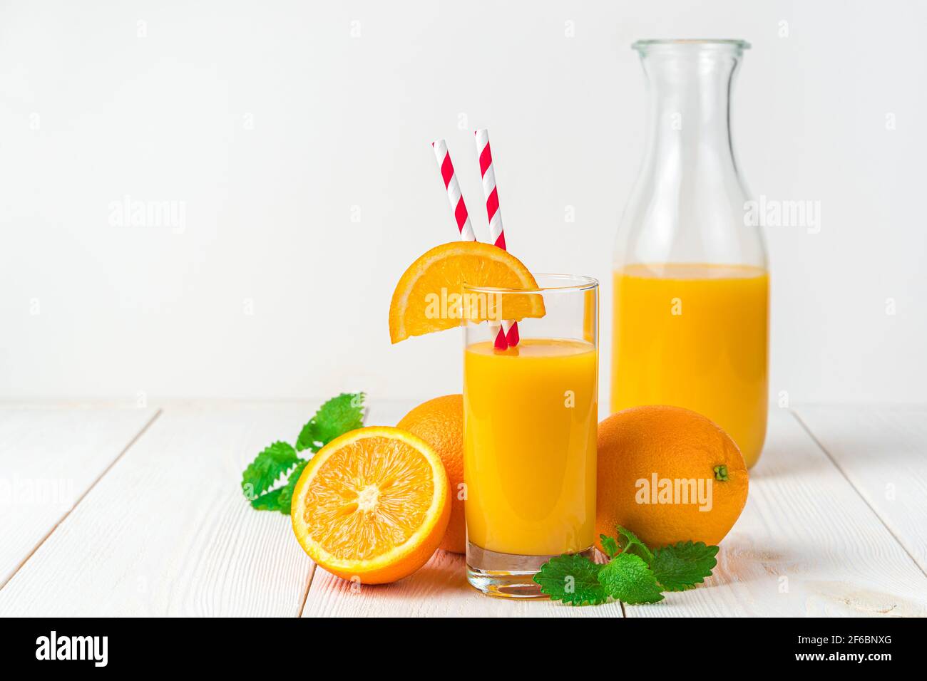 Frisch gepresster Orangensaft und Orangen auf hellem Hintergrund. Stockfoto