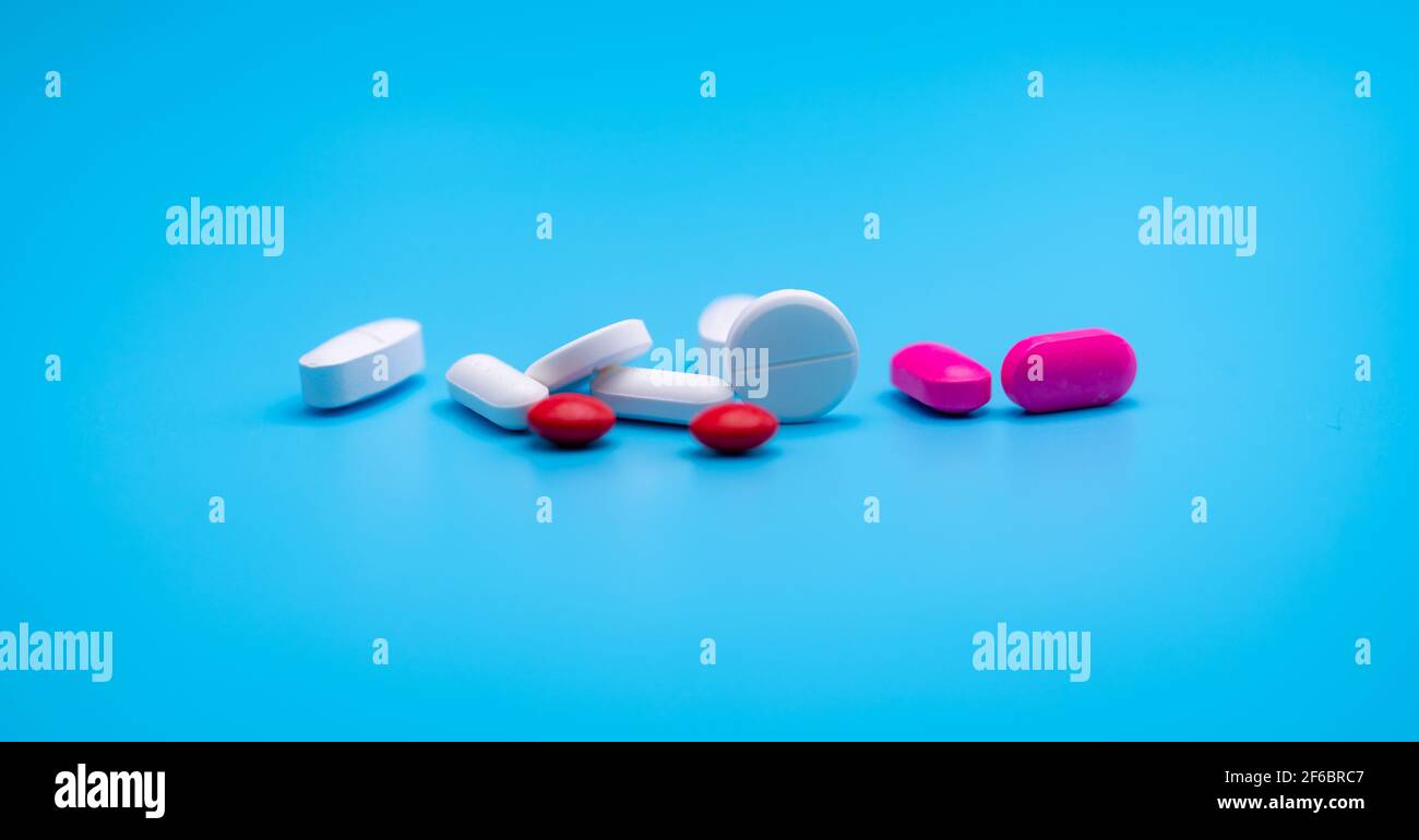 Weiße und rosa Tabletten Pille auf blauem Hintergrund mit Kopieplatz verteilt. Webbanner der Apotheke. Pharmaindustrie. Runde und ovale Tabletten Pillen. Stockfoto