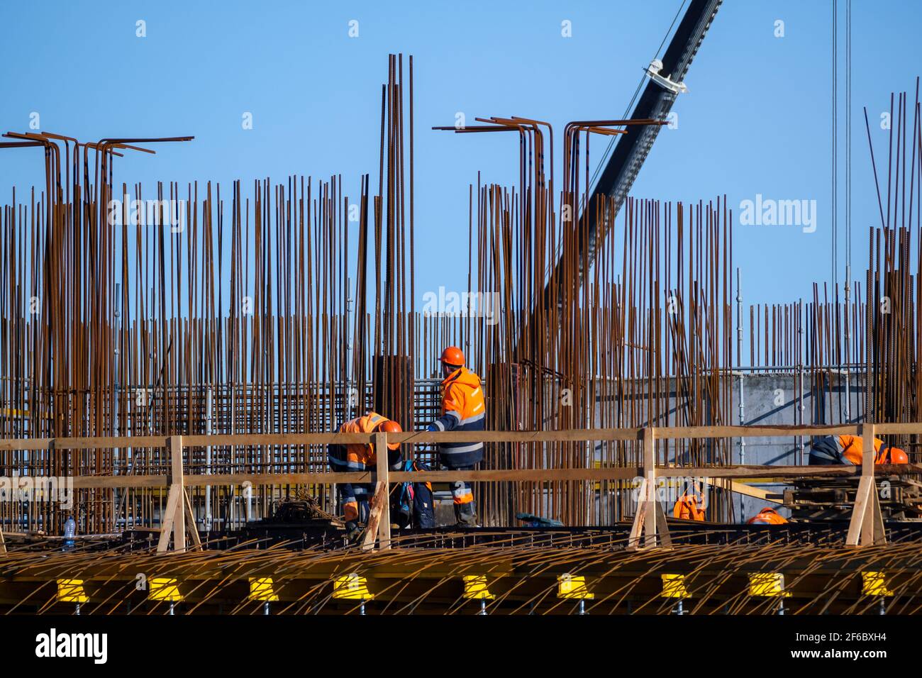 Anonyme männliche Bauherren in Uniform arbeiten auf Brücke in der Nähe von Metall Stangen gegen wolkenlosen blauen Himmel auf Baustelle Stockfoto