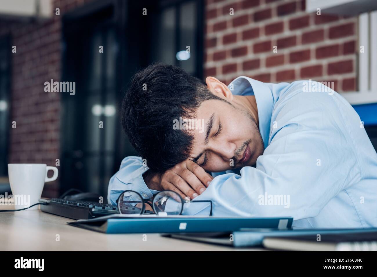 Müde asiatische Geschäftsmann schlafen auf Schreibtisch Tisch im Amt. arbeiten hart und spät. burn out-Syndrom Stockfoto