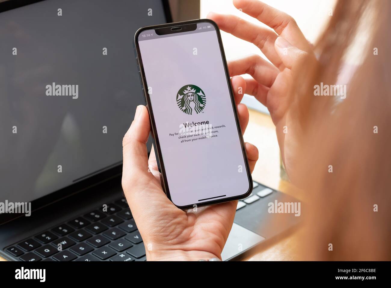 Chiang Mai, Thailand : Mär 7 2021 : EINE Frau hält iPhone 12 mit Starbucks Logo auf dem Bildschirm in Starbucks Coffee Shop. Stockfoto