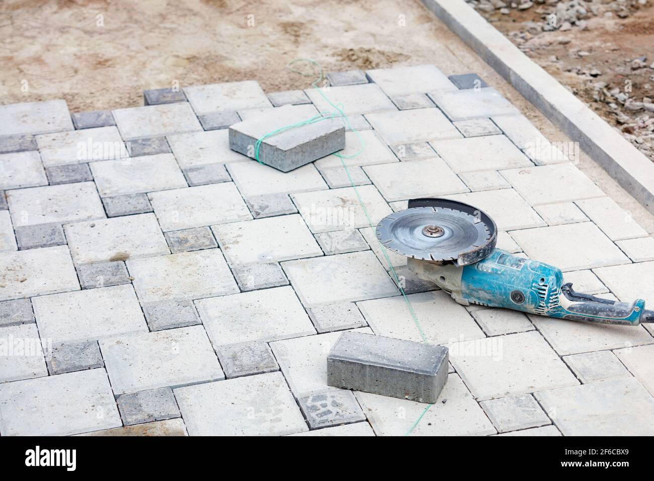 Ein abgenutzter elektrischer Winkelschleifer mit einer Diamant-Trennscheibe auf einem Einbauarbeitsplatz. Selektiver Fokus, Kopierbereich. Stockfoto