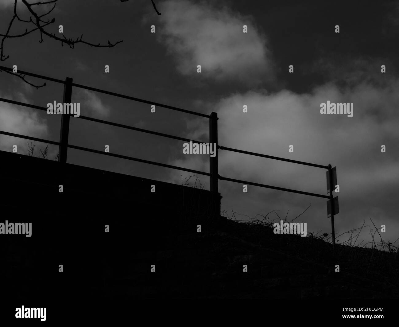 Moody Schwarz-Weiß-Fotografie einer Eisenbahnbrücke gegen einen bewölkten Himmel. Stockfoto