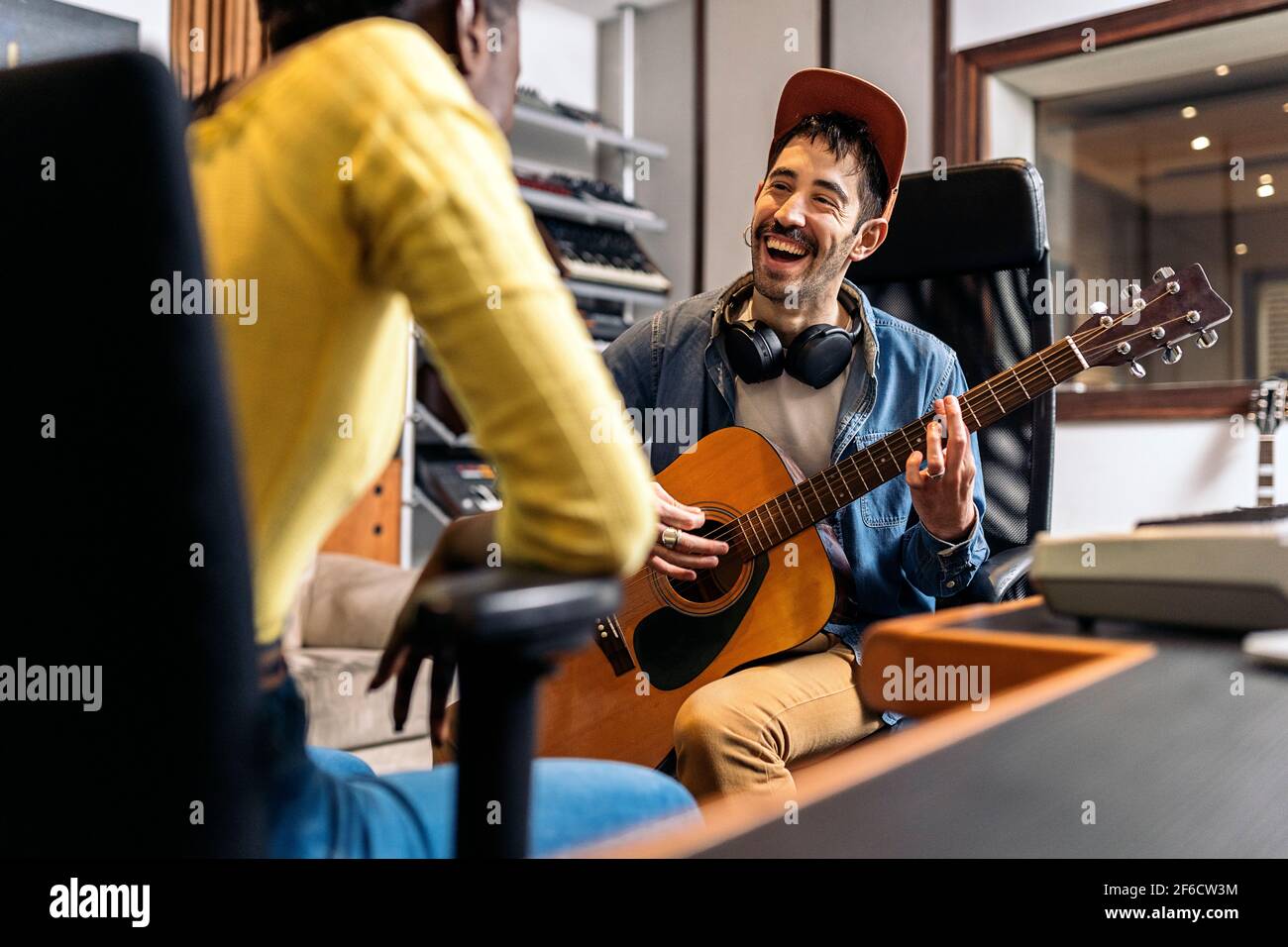 Stock Foto von glücklichen Künstler im Musikstudio spielt die Gitarre neben unerkannte schwarze Frau. Stockfoto