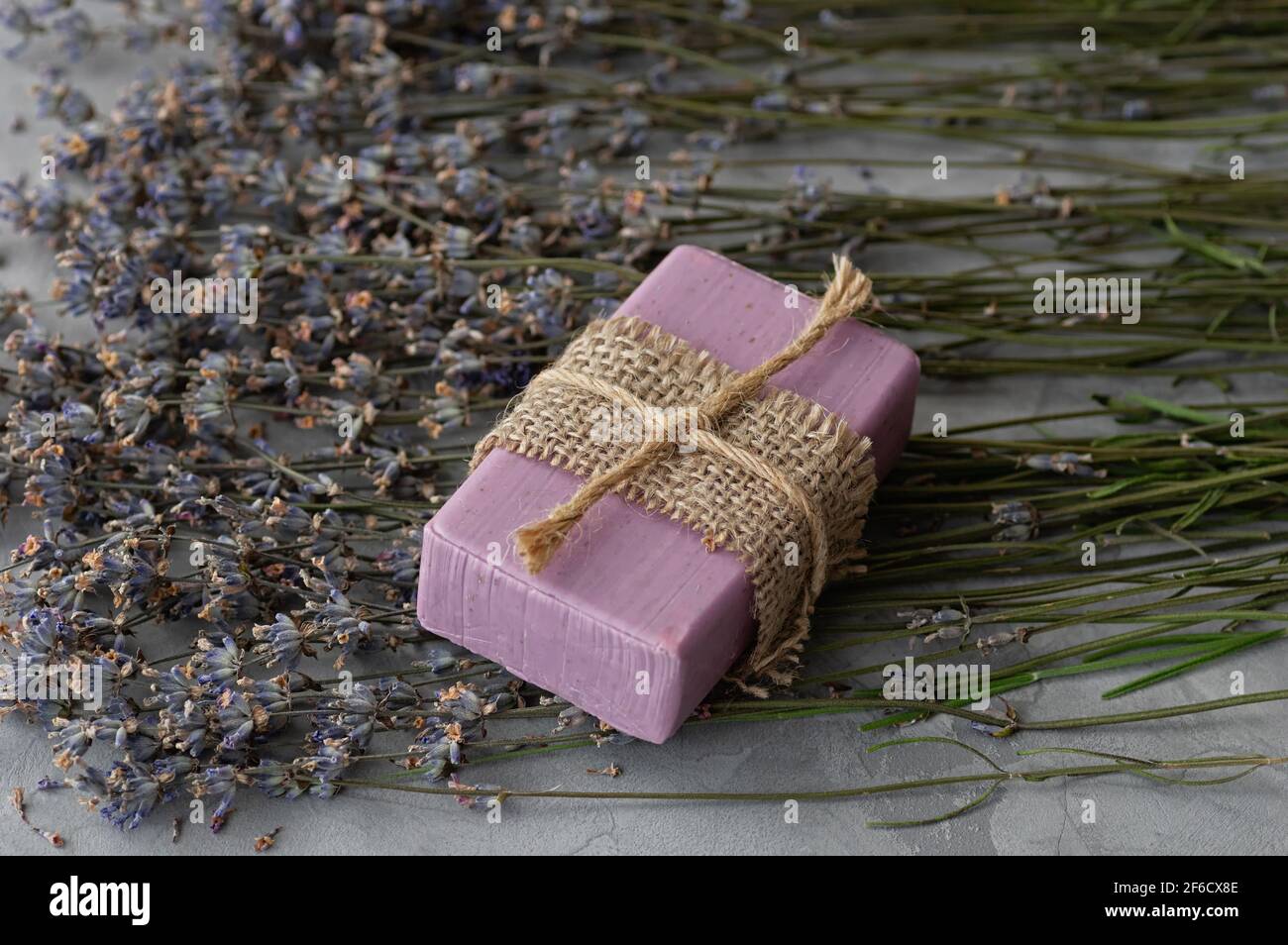Handgemachte Seife mit natürlichen Inhaltsstoffen und trockenen Lavendelblüten auf grauem Betongrund. Nahaufnahme. Stockfoto
