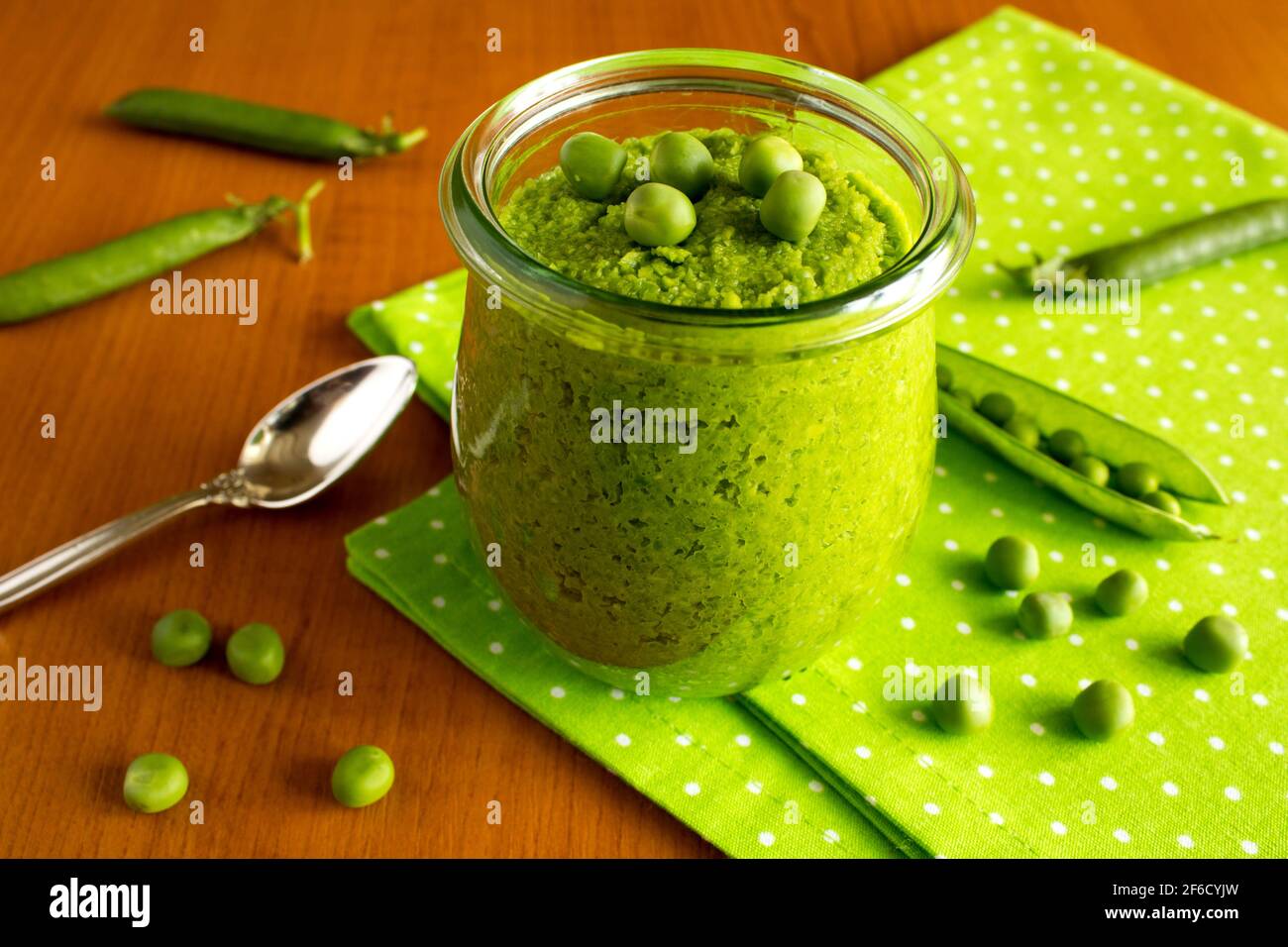 Kinderpüree mit Erbsen im Glas auf dem Grüne Serviette Stockfoto