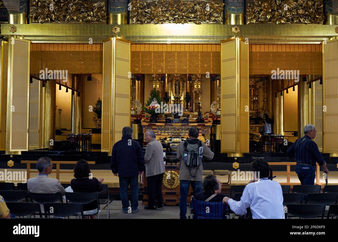 Tokio, Japan - 23. Oktober 2019: Der Blick auf die Haupthalle des buddhistischen Tsukiji Hongan-ji Tempels mit Menschen, die vor dem Altar mit der Statue beten Stockfoto