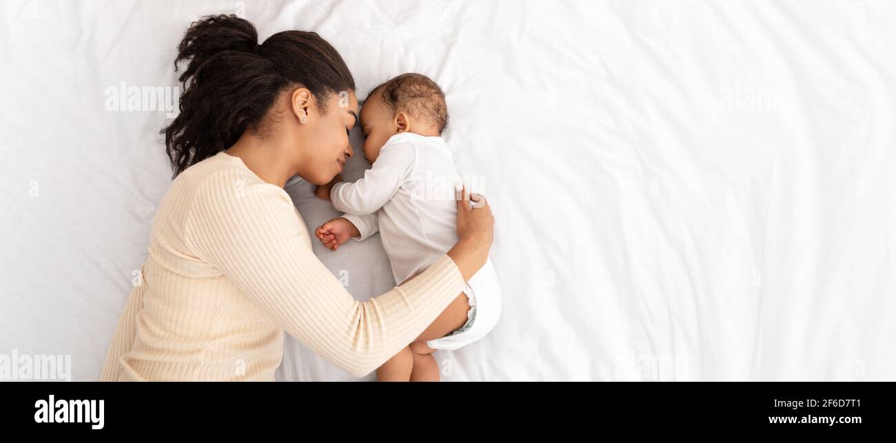 Afrikanische Mutter Umarmt Schlafen Baby Liegend Im Bett Indoor, High-Angle Stockfoto