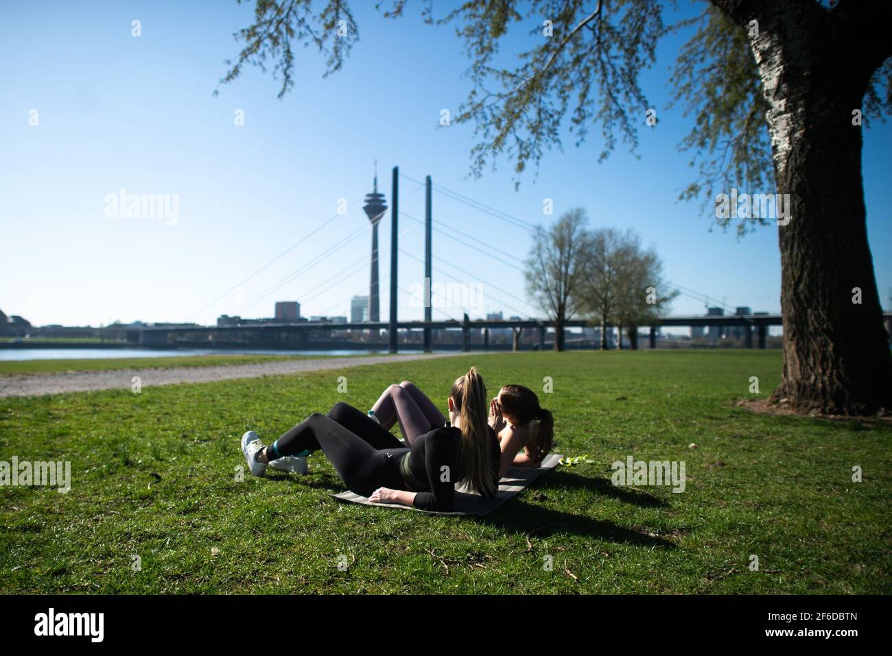 Dusseldorf Deutschland Marz 2021 31st Zwei Frauen Liegen In Der Sonne Auf Den Rheinwiesen In Oberkassel Wahrend Im Hintergrund Der Rheinturm Und Die Rheinkniebrucke Zu Sehen Sind Meteorologen Prognostizieren Fruhlingshaftes Wetter Fur
