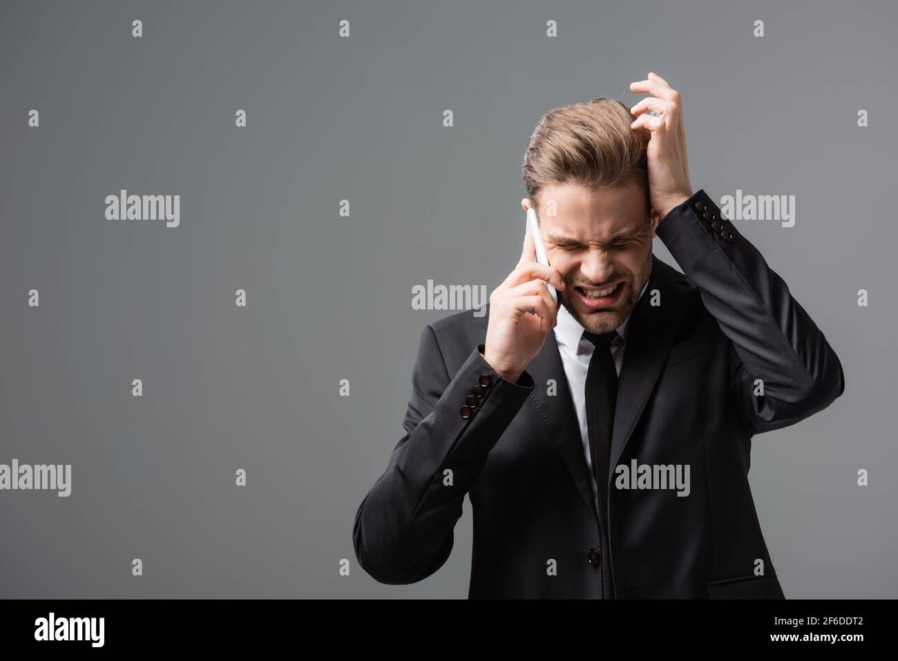Gestresster Manager, der am Handy sprach und den Kopf isoliert anberührte Grau Stockfoto