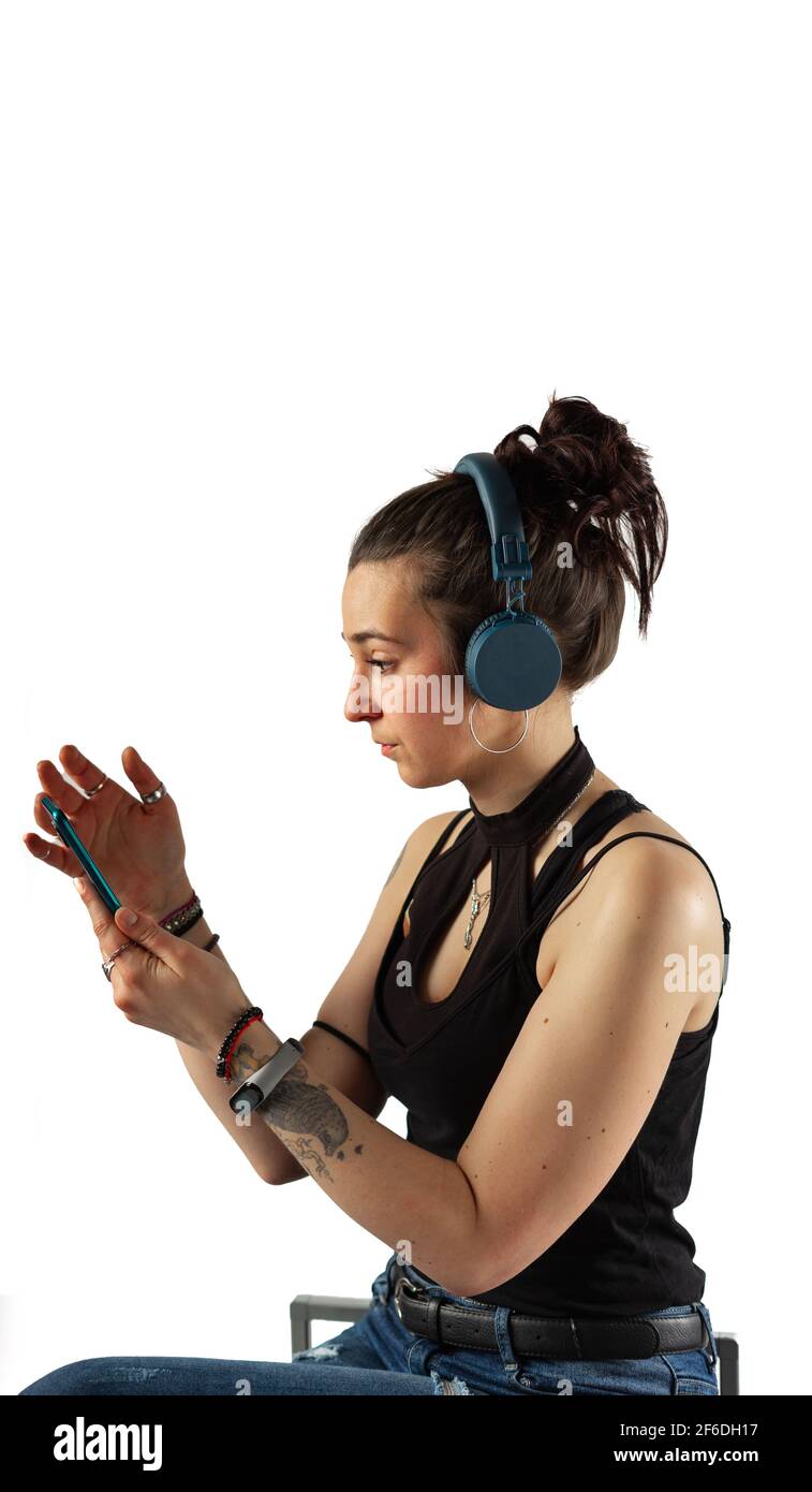 Alternative Mädchen mit Tattoos mit ihrem Handy und drahtlos Kopfhörer mit ärmellosem Oberteil Stockfoto