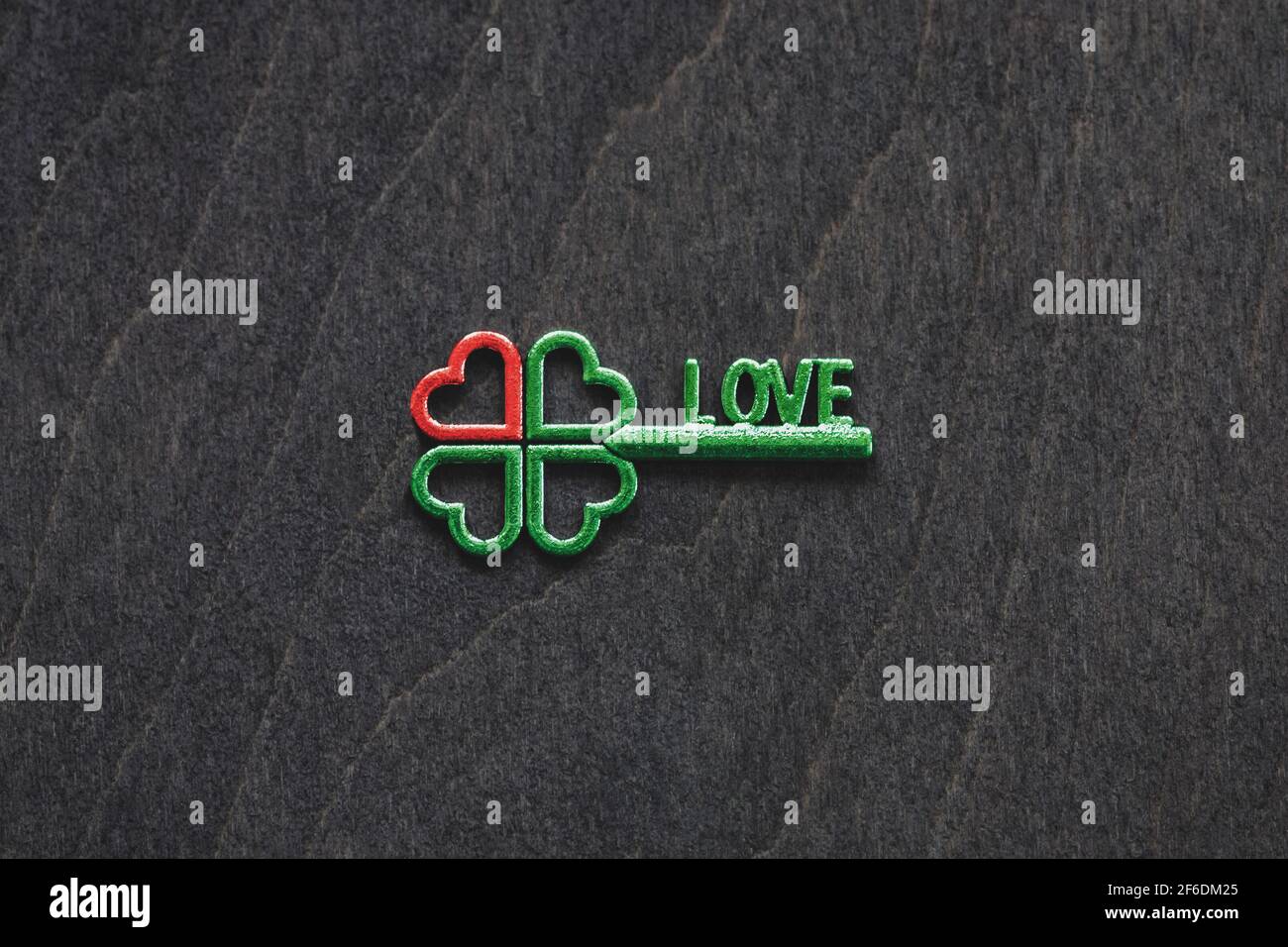 Vierblättriger grüner Kleeblatt-Schlüssel mit rotem Herz als Symbol Von Liebe und Glück Konzept Stockfoto
