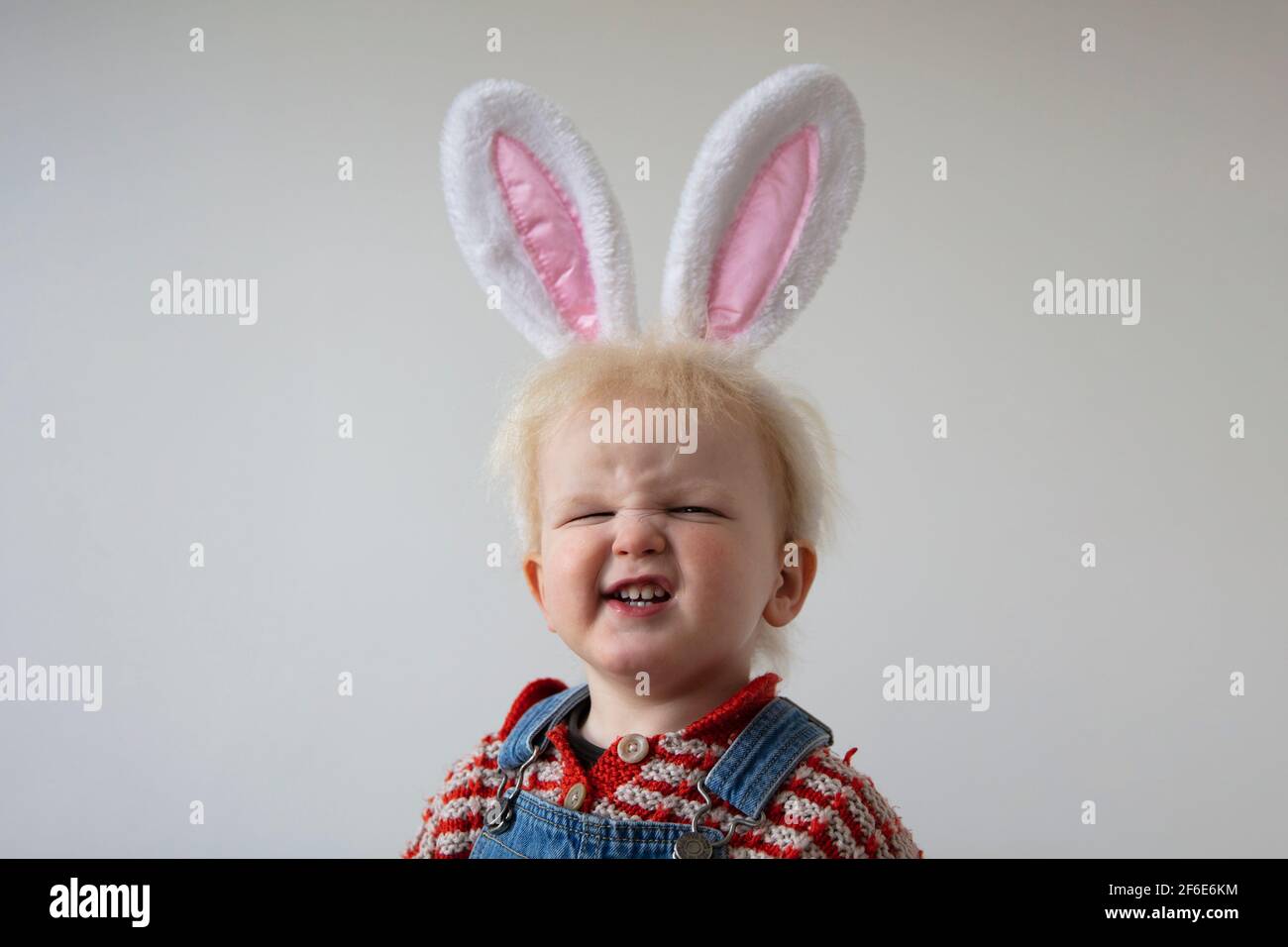 Ein niedliches Kleinkind trägt osterhasen Ohren machen eine alberne Lächelndes Gesicht Stockfoto