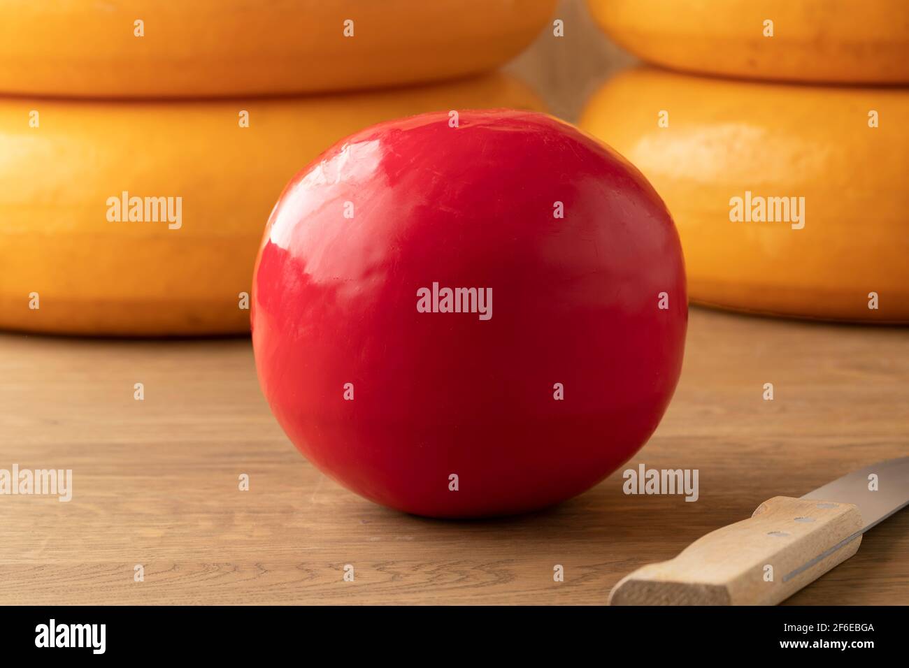 Ganze holländische rote Edam Käse auf einem Schneidebrett und Große Käsesorten im Hintergrund Stockfoto