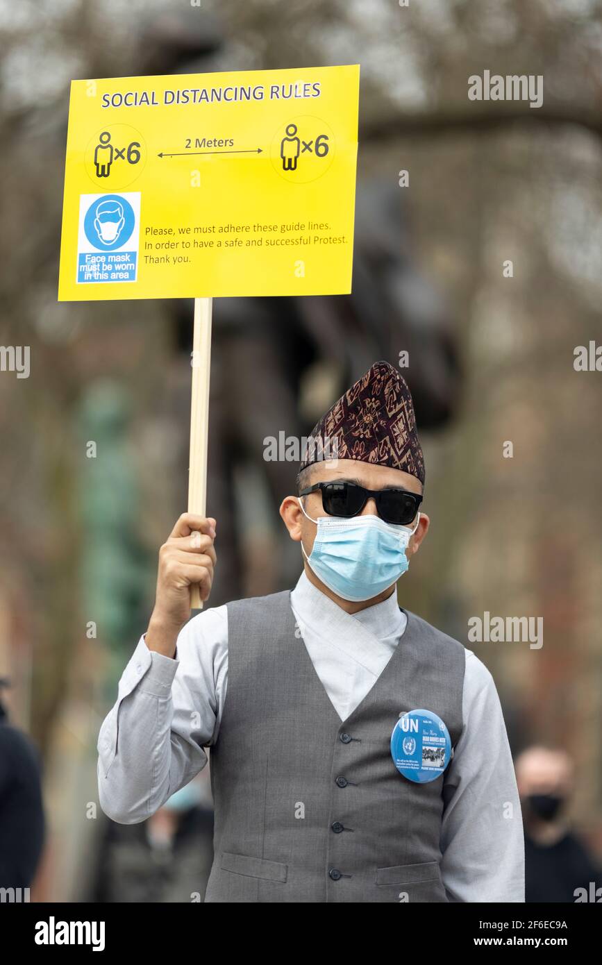 London, Großbritannien. März 2021, 31st. Ein Protestant mit einem sozial-distanzierenden Plakat auf dem Parliament Square. Demonstranten versammelten sich auf dem Parliament Square - mit Gesichtsmasken und beobachteten eine soziale Distanzierung -, bevor sie zur chinesischen Botschaft marschierten, um Solidarität mit dem Volk von Myanmar gegen den Militärputsch und die staatlichen Tötungen von Zivilisten zu zeigen. Vor der Botschaft wurden Reden gehalten. Seit Beginn des Militärputsches am 1st. Februar wurden in Myanmar mehr als 520 Menschen von Sicherheitskräften getötet. Am vergangenen Samstag war der gewalttätigste Tag, an dem mehr als 100 Menschen getötet wurden. Kredit: Joshua Windsor/ Stockfoto