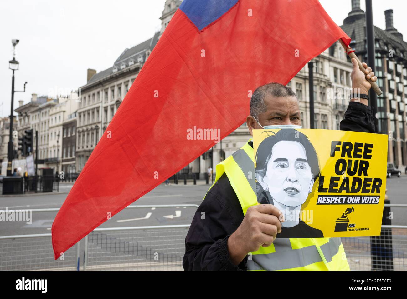 London, Großbritannien. März 2021, 31st. Ein Protestler mit einer Fahne und einem Plakat mit der Aufschrift "Befreie unseren Anführer. Respektieren Sie unsere Stimmen" auf dem Parliament Square. Demonstranten versammelten sich auf dem Parliament Square - mit Gesichtsmasken und beobachteten eine soziale Distanzierung -, bevor sie zur chinesischen Botschaft marschierten, um Solidarität mit dem Volk von Myanmar gegen den Militärputsch und die staatlichen Tötungen von Zivilisten zu zeigen. Vor der Botschaft wurden Reden gehalten. Seit Beginn des Militärputsches am 1st. Februar wurden in Myanmar mehr als 520 Menschen von Sicherheitskräften getötet. Am vergangenen Samstag war der gewalttätigste Tag, an dem mehr als 100 Menschen waren Stockfoto