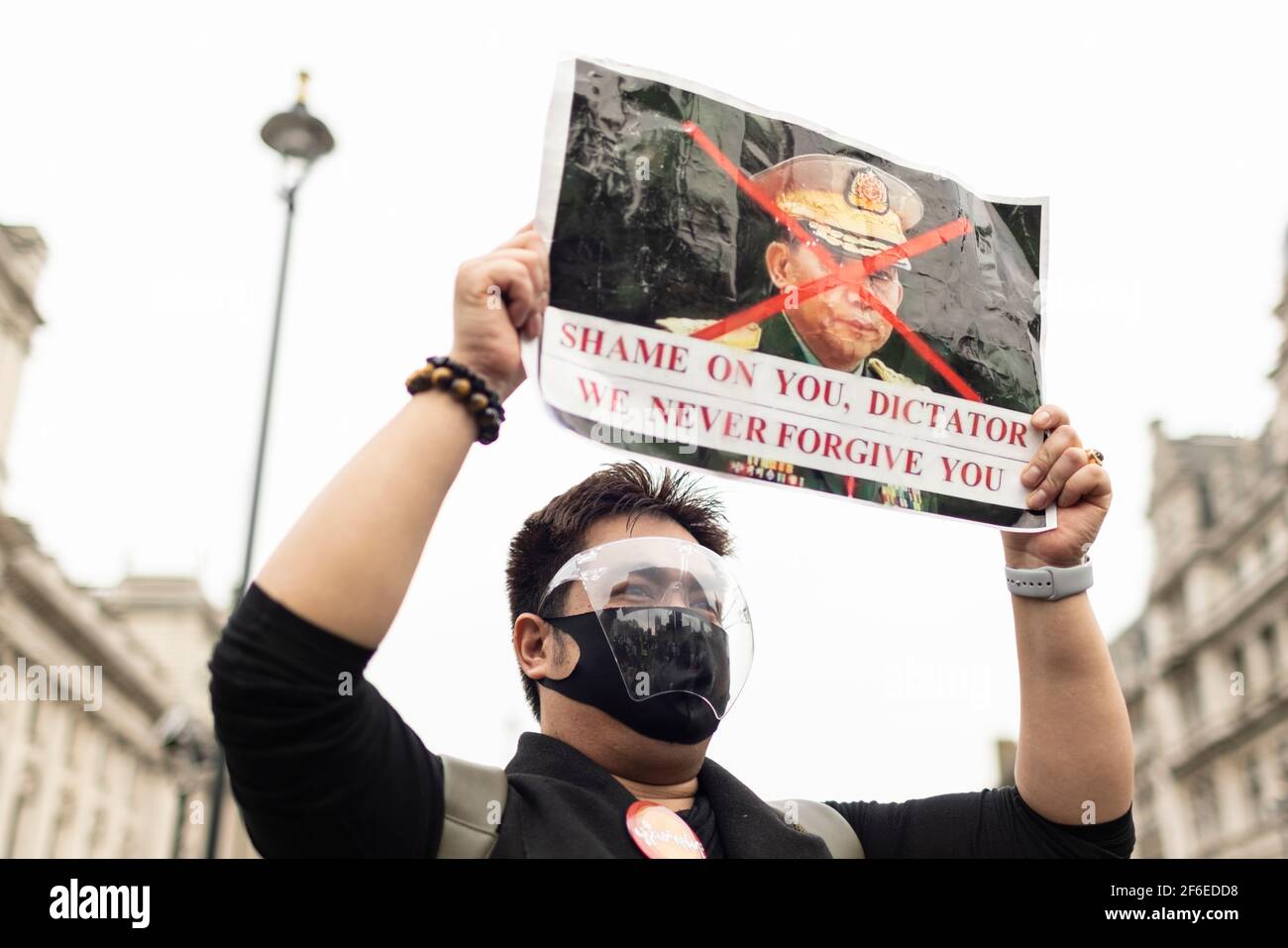 London, Großbritannien. März 2021, 31st. Ein Protestler in einem Gesichtsschild hält ein Plakat mit der Aufschrift "Schande über dich, Diktator. Wir verzeihen Ihnen nie auf dem Parliament Square. Demonstranten versammelten sich auf dem Parliament Square - mit Gesichtsmasken und beobachteten eine soziale Distanzierung -, bevor sie zur chinesischen Botschaft marschierten, um Solidarität mit dem Volk von Myanmar gegen den Militärputsch und die staatlichen Tötungen von Zivilisten zu zeigen. Vor der Botschaft wurden Reden gehalten. Seit Beginn des Militärputsches am 1st. Februar wurden in Myanmar mehr als 520 Menschen von Sicherheitskräften getötet. Letzten Samstag war der gewalttätigste Tag, wenn Stockfoto