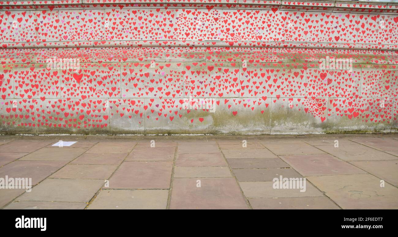 London, Großbritannien. 31st. März 2021. Rote Herzen an der National Covid Memorial Wall. Fast 150.000 Herzen werden von Freiwilligen gemalt, eines für jedes Covid-19-Opfer in Großbritannien bis heute, an der Wand vor dem St. Thomas' Hospital gegenüber dem Parlamentsgebäude. Stockfoto