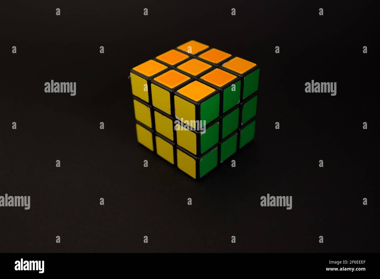 Avola, Italien - März 31st 2021: Nahaufnahme eines gelösten Rubik-Würfels auf schwarzem Hintergrund. Das Objekt zeigt seine gelben, orangefarbenen und grünen Gesichter. Es war Inv Stockfoto