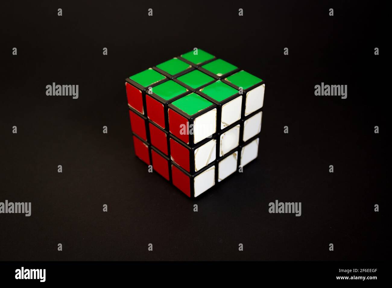 Avola, Italien - März 31st 2021: Nahaufnahme eines gelösten Rubik-Würfels auf schwarzem Hintergrund. Das Objekt zeigt seine roten, weißen und grünen Gesichter. Es war invente Stockfoto