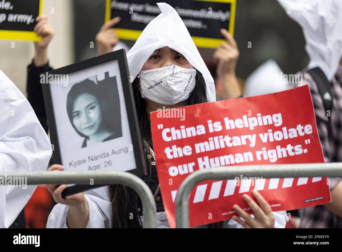 London, Großbritannien. März 2021, 31st. Ein in Weiß gekleideter Protestler hält ein Foto eines verstorbenen Opfers und ein Plakat mit der Aufschrift "China hilft dem Militär, unsere Menschenrechte zu verletzen" vor der chinesischen Botschaft. Demonstranten versammelten sich auf dem Parliament Square - mit Gesichtsmasken und beobachteten eine soziale Distanzierung -, bevor sie zur chinesischen Botschaft marschierten, um Solidarität mit dem Volk von Myanmar gegen den Militärputsch und die staatlichen Tötungen von Zivilisten zu zeigen. Vor der Botschaft wurden Reden gehalten. Seit Beginn des Militärputsches am 1st. Februar wurden in Myanmar mehr als 520 Menschen durch Sicherheitsdienste getötet Stockfoto