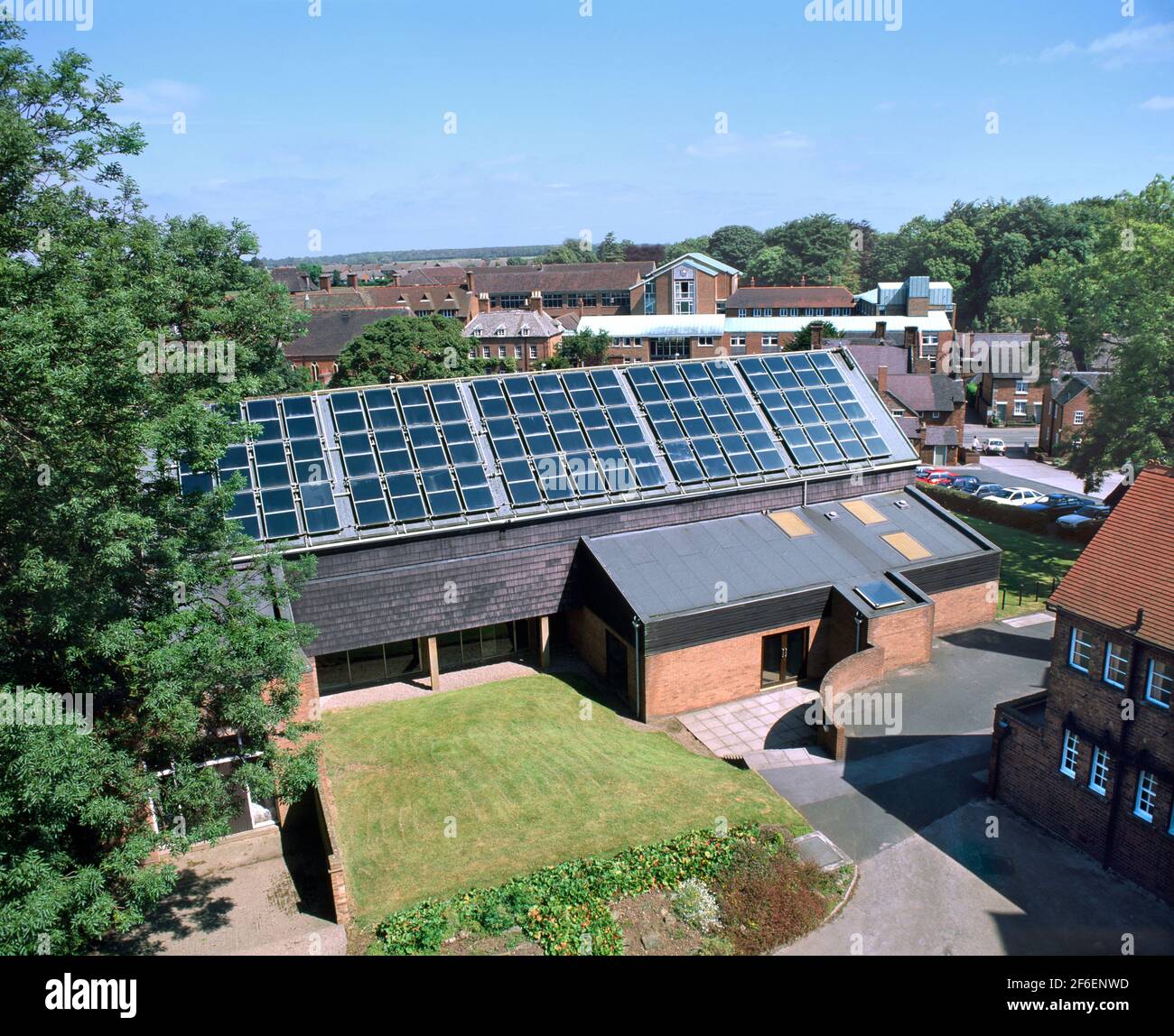 Eine Reihe von auf dem Dach montierten Sonnenkollektoren zum Erhitzen von Wasser für einen Swimmingpool im darunter liegenden Gebäude. Abbot's Bromley School, Staffordshire. Stockfoto