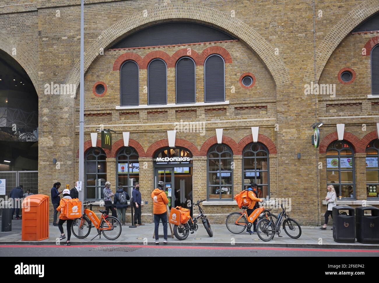 Lieferfahrer, die für Just Eat arbeiten, warten vor dem McDonalds-Restaurant an der London Bridge Station, Tooley Street, London, Großbritannien, auf Bestellungen Stockfoto