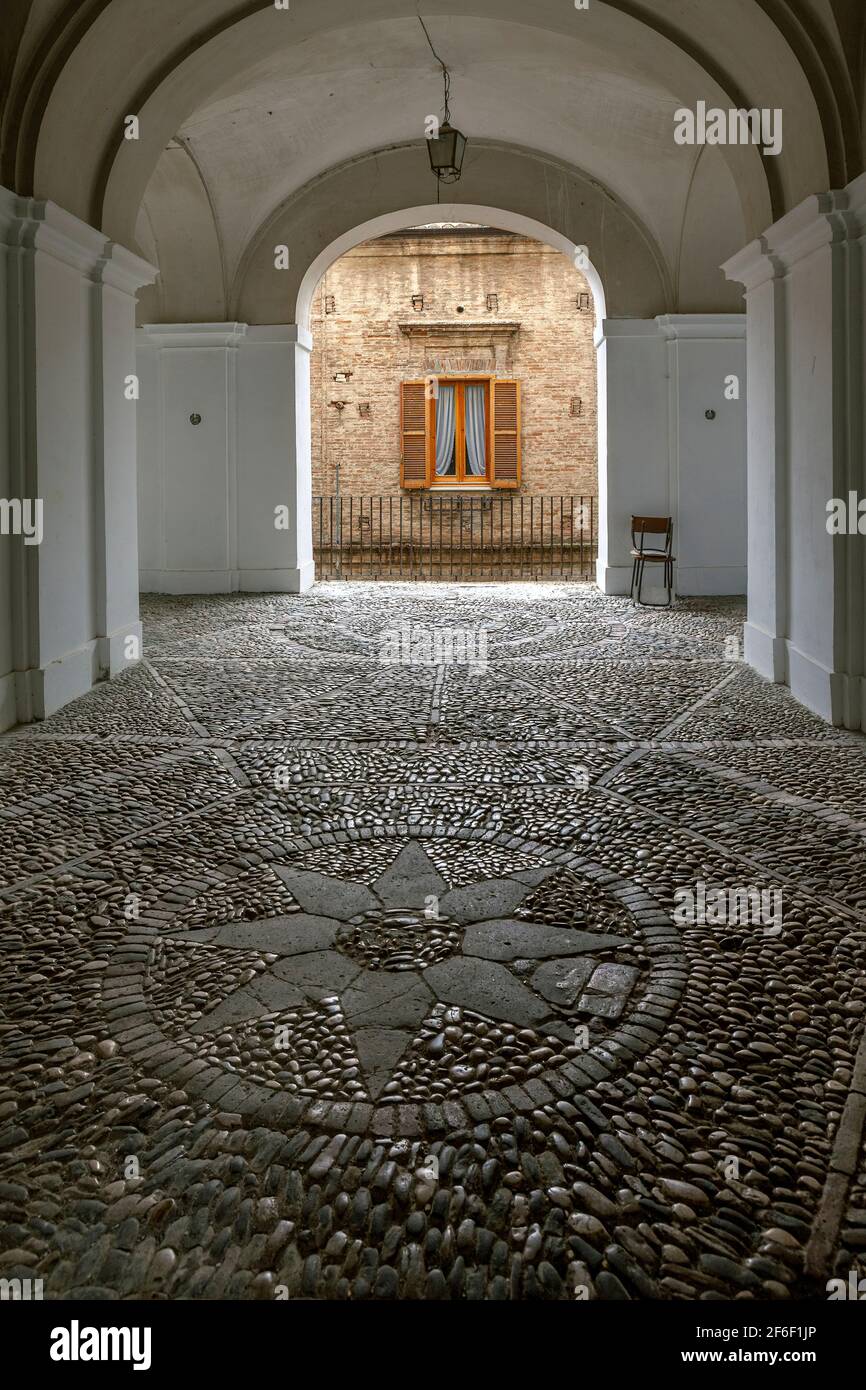 Überdachte Passage mit Pavé-Boden und Dekorationen auf dem Boden einer Kompassrose in einem Kreis. Penne, Provinz Pescara, Abruzzen, Italien, Europa Stockfoto