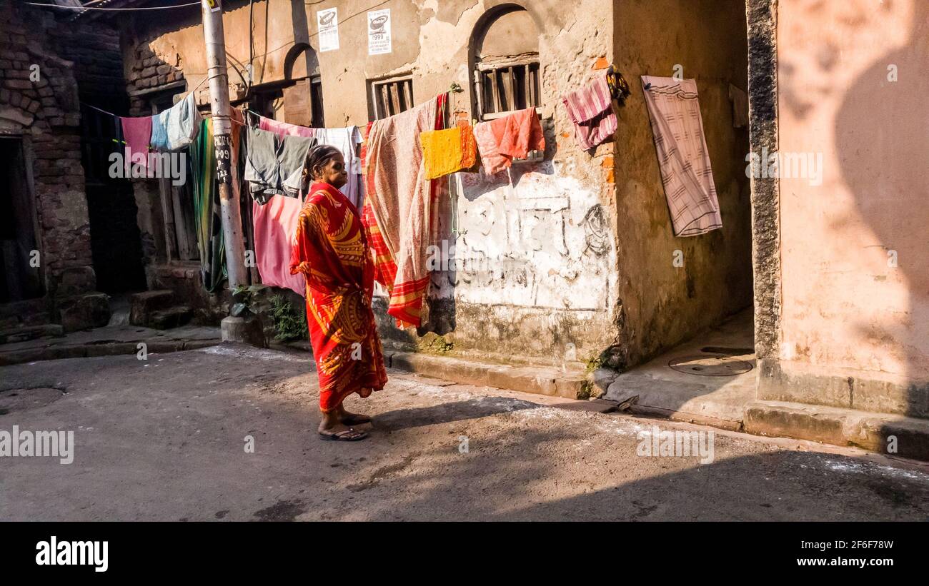 Kalkutta, Westbengalen, Indien - 2018. Januar: Eine indische Frau, die einen bunten Sari trägt, steht vor den rustikalen Wänden eines Hauses auf den Straßen der Stockfoto