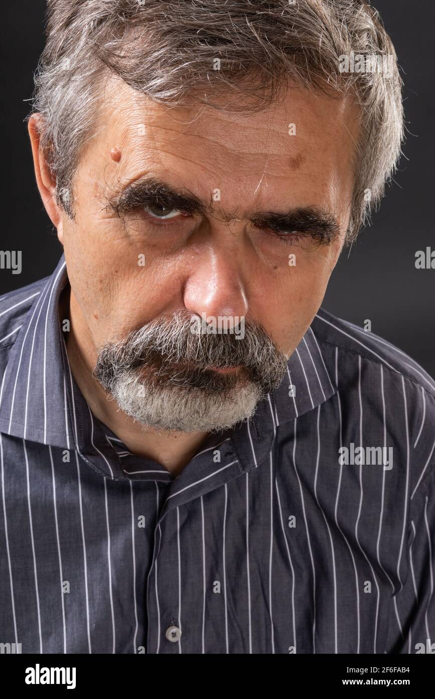 Älterer wütender grauhaariger Mann, der mürrisch aussackte Stockfoto