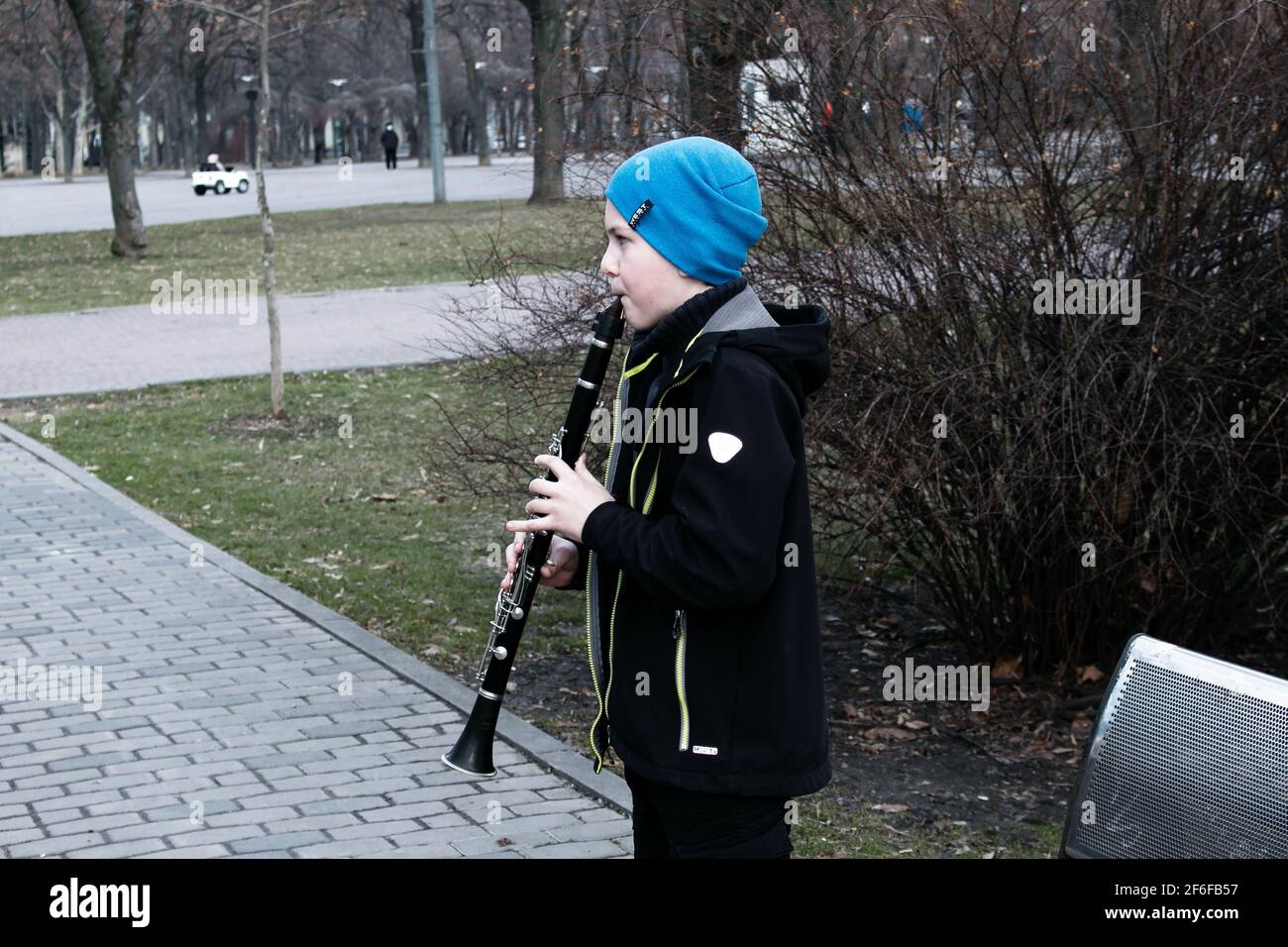 Dnepropetrovsk, Ukraine - 03.29.2021: Ein Junge im Park spielt Klarinette. Das Kind ist gut gelaunt. Stockfoto