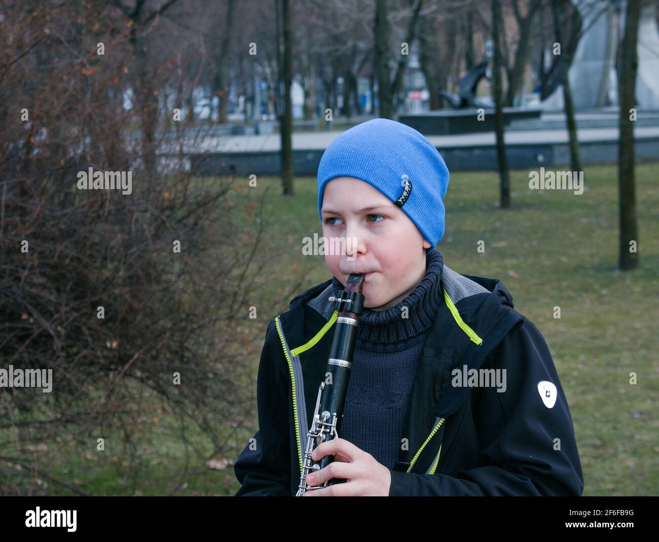 Dnepropetrovsk, Ukraine - 03.29.2021: Ein Junge im Park spielt Klarinette. Das Kind ist gut gelaunt. Stockfoto