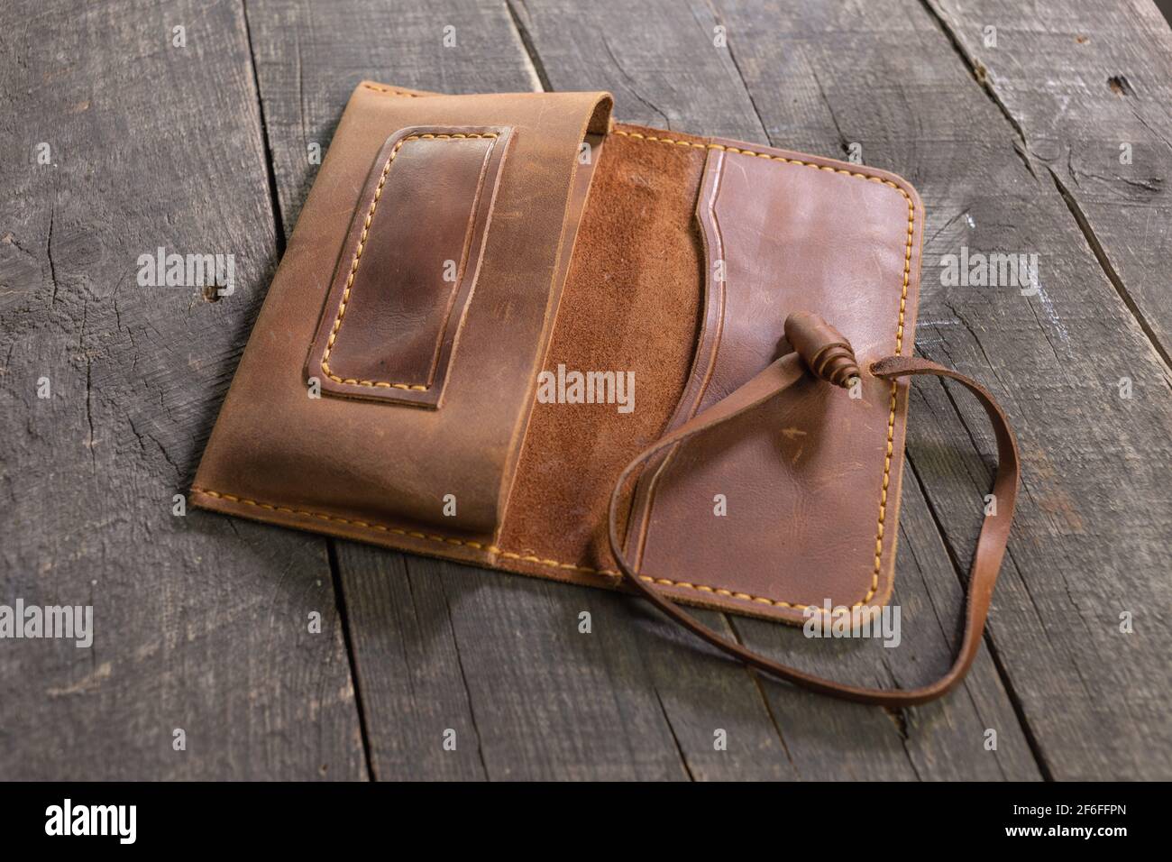 Handgemachte braune Tabaktasche aus Leder auf Holzhintergrund. DIY. Stockfoto