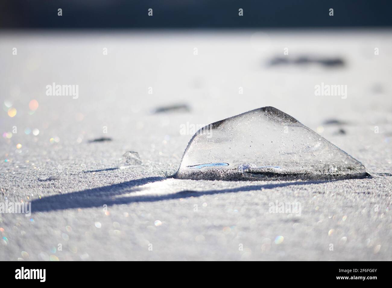 Ein unregelmäßiger, transparenter Eisblock, durch den Sonnenlicht hindurch geht. Atemberaubende natürliche Eiskonstruktion auf der gefrorenen Oberfläche des Sees Stockfoto