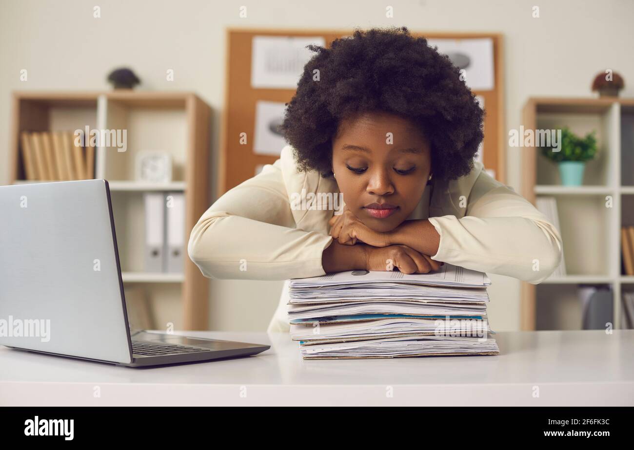 afroamerikanische Büroangestellte schläft auf Papierstapel Am Schreibtisch Stockfoto