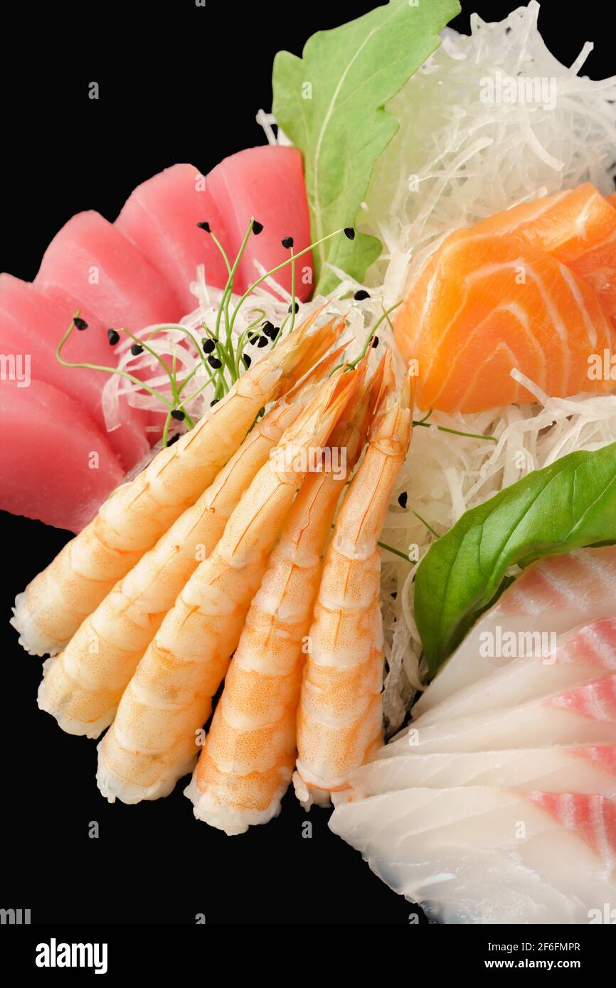 Verschiedene Sashimi-Lachs, Seebarsch, Thunfisch, Tiger-Garnelen. Japanisches Essen. Isoliert auf schwarzem Hintergrund Stockfoto