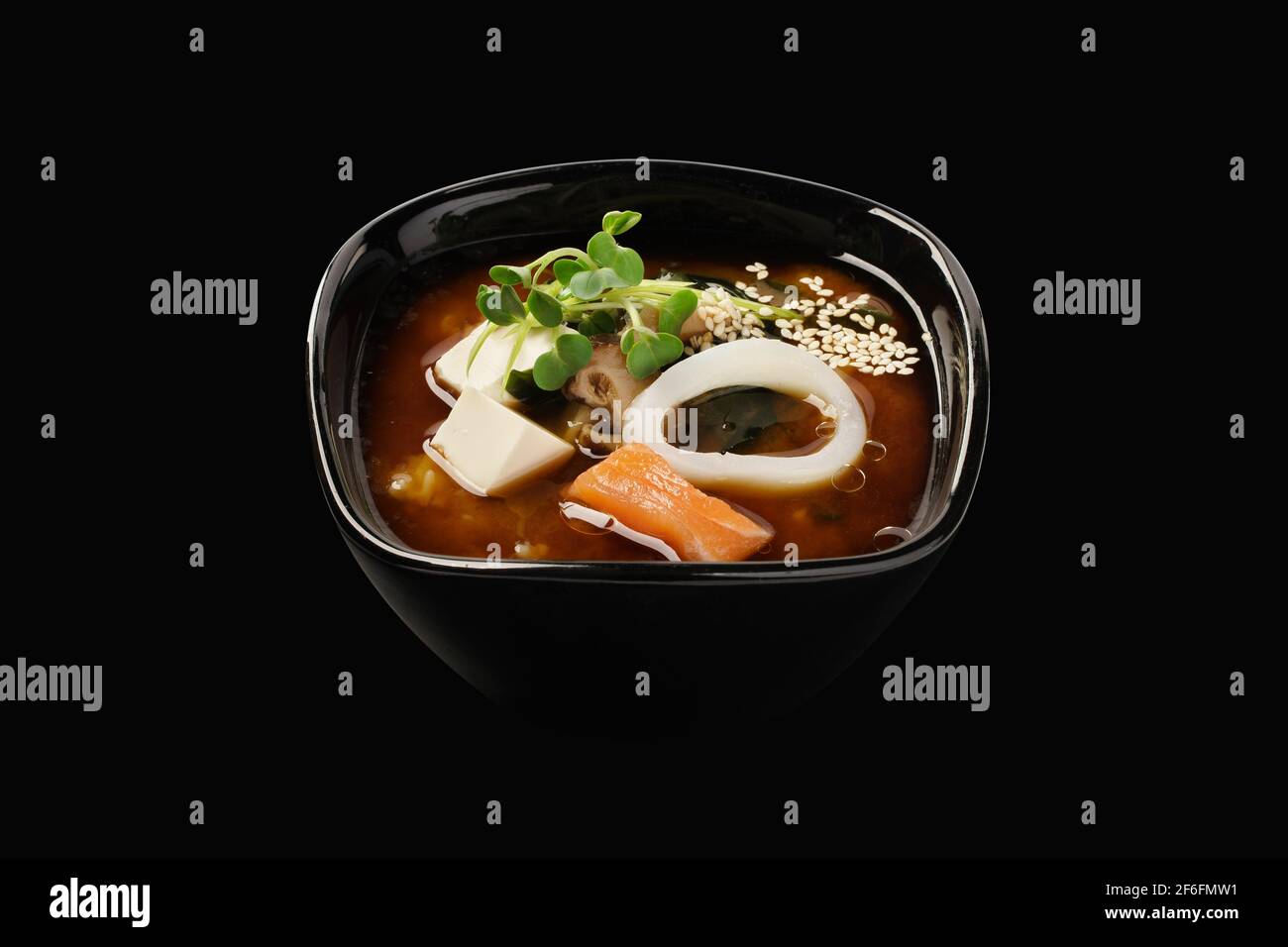 Miso-Suppe mit Lachs und Tintenfisch, Brühe, Wakame-Algen, Shiitake-Pilze, Tofu-Käse, Grüne Zwiebeln, Lauch, Sesamsamen. Japanisches Essen. Isoliert ein Stockfoto