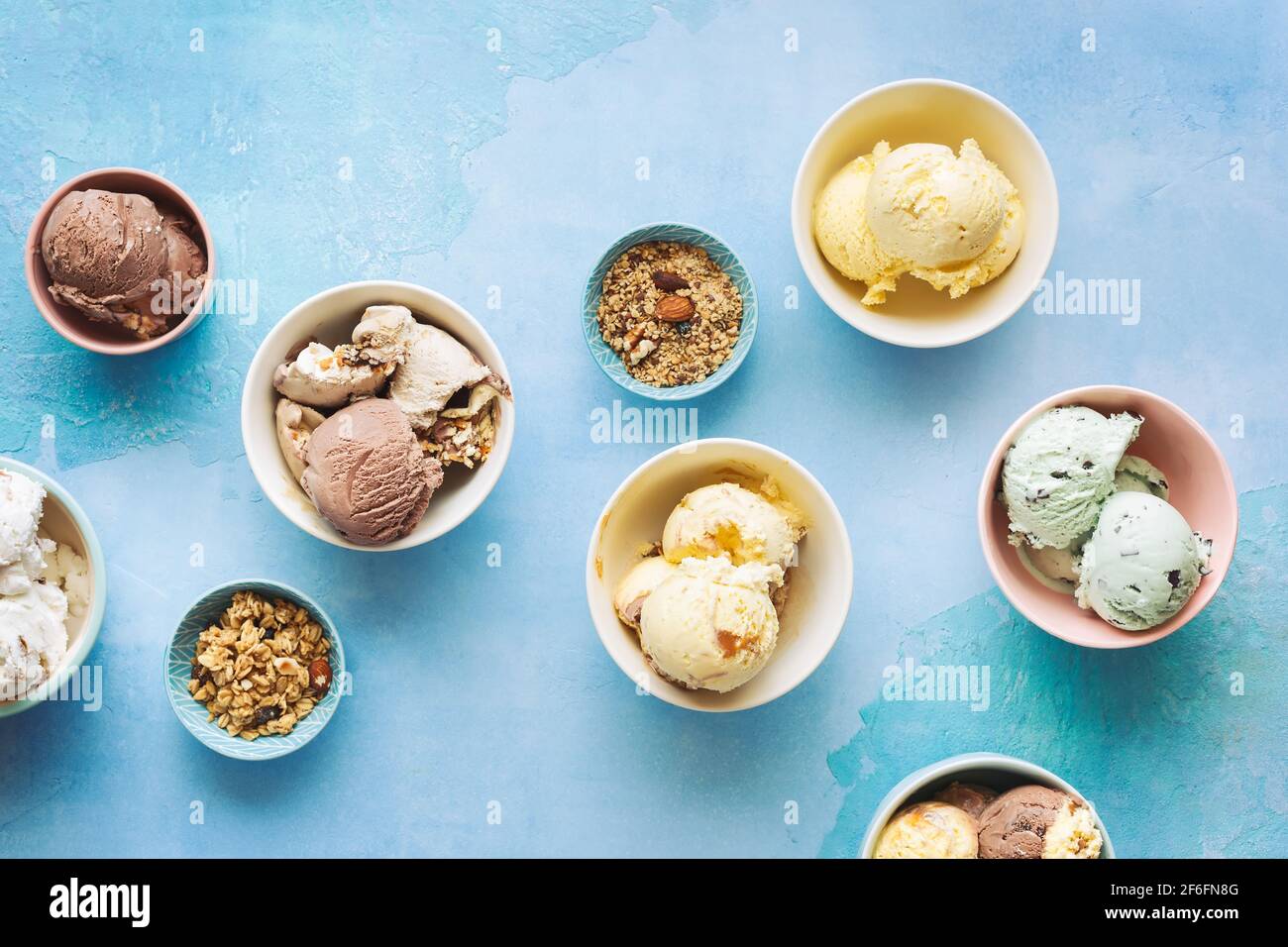 Verschiedene Eisdesserts in Schüsseln auf rustikalem blauen Hintergrund, Draufsicht, Leerraum Stockfoto