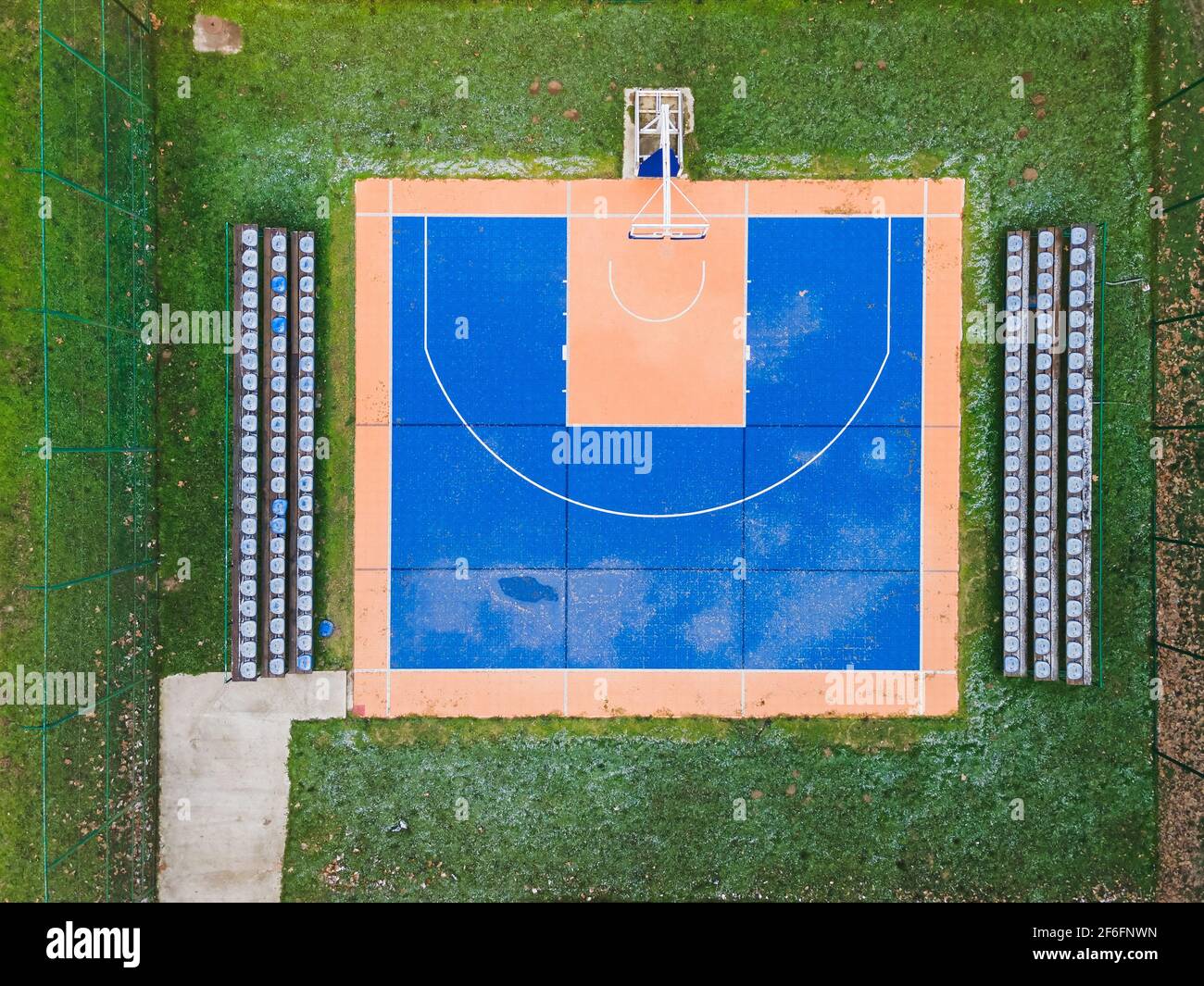 Buntes Basketballfeld von oben. Outdoor-Sportplatz mit blauer und orangefarbener Oberfläche für Basketball, Lampen und Bänke für Zuschauer Stockfoto